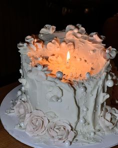 there is a white cake with flowers on the plate and a candle in the middle