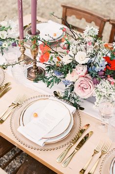 the table is set with flowers and gold place settings for an elegant dinner or reception