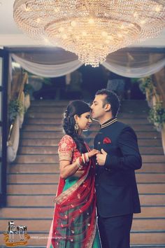 a man and woman standing next to each other under a chandelier