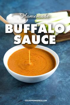 homemade buffalo sauce being poured into a white bowl with celery sticks in the background