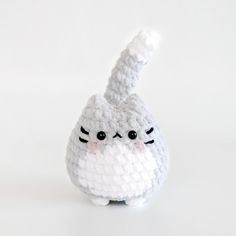 a crocheted white cat with black eyes sitting on top of a white surface