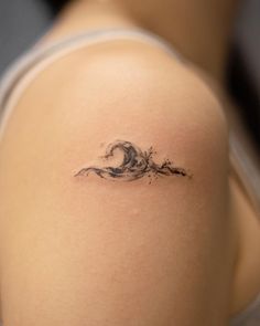 a woman's shoulder with a wave tattoo on it