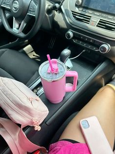 a pink coffee cup sitting on top of a car dashboard