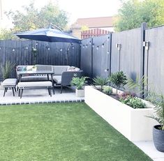 an outdoor patio area with grass and potted plants on the side of the fence