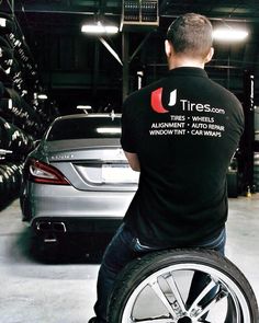 a man sitting on top of a wheel chair next to a car in a garage