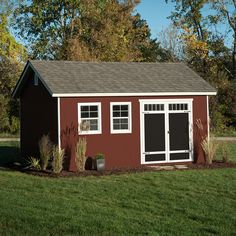 a small red shed sitting on top of a lush green field