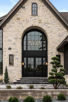 a stone house with black double doors and glass windows on the front door is shown