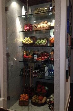 a glass display case filled with lots of fruits and veggies in a kitchen