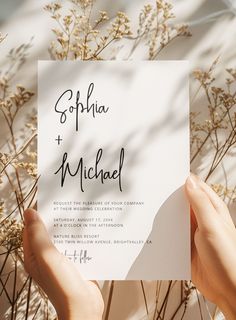 two hands holding up a wedding card with the word'gorhia and michael'written on it