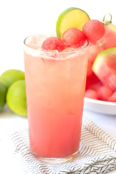 a glass filled with watermelon and limeade next to a bowl of fruit