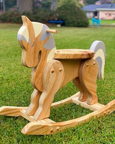 a wooden rocking horse sitting in the grass