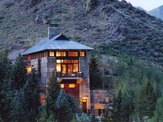 a house on the side of a mountain with lights shining in it's windows