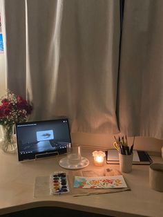 a laptop computer sitting on top of a desk next to a vase filled with flowers