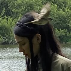 a woman with long hair standing next to a river