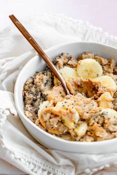 a white bowl filled with oatmeal and bananas on top of a table