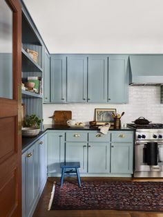 a kitchen with blue cabinets and an area rug on the floor in front of it