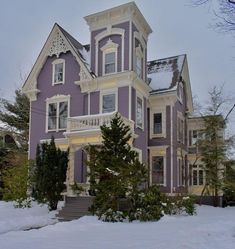 a large purple house with white trim and snow on the ground in front of it