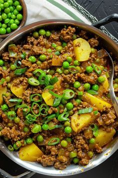 a bowl filled with peas, potatoes and meat on top of a table next to green peas