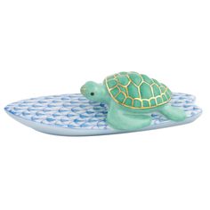 a green turtle sitting on top of a blue and white plate