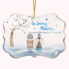 an ornament with the words in loving memory and two people sitting under a tree