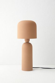 a beige lamp sitting on top of a white table next to a black light bulb