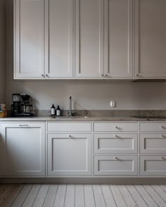 a kitchen with white cabinets and wood floors