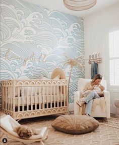 a woman sitting on the floor next to a baby crib