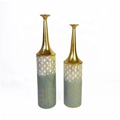 two gold vases sitting next to each other on a white surface with no one around them