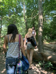 two women walking in the woods with their backs to each other and one carrying a blue bag