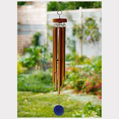 a wind chime hanging from the side of a garden