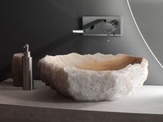 a bathroom sink with a stone bowl on the counter next to a soap dispenser