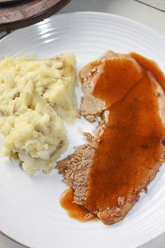 a white plate topped with meat, mashed potatoes and gravy