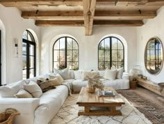 a living room filled with lots of white furniture and large arched windows in the wall