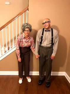 an older couple standing next to each other in front of a stair case and railing