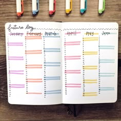 an open planner with markers and pens on the pages next to it, in front of a wooden background