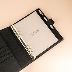 a black binder with a note book and pen