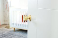 a white door with a gold handle in a baby's nursery room, next to a crib