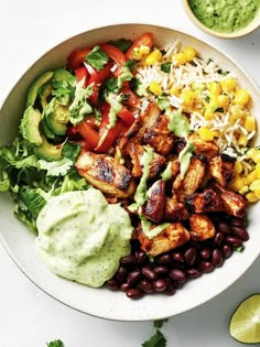 a white bowl filled with tacos, beans and guacamole on top of a table