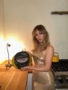 a woman in a gold dress holding a cake