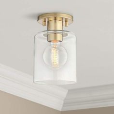 a light fixture with a clear glass cover on the ceiling and gold trim around it