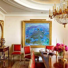 a dining room table with red chairs and a painting hanging on the wall above it