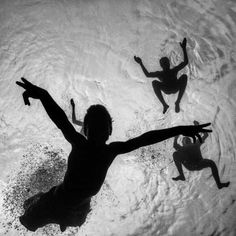 three people in the water with their arms spread out and one person holding his hands up