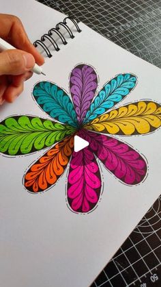 someone is drawing with colored pencils on top of a piece of paper that has an image of a flower