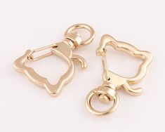 two pairs of gold tone metal ear clips with an animal design on each end and a round hole in the middle