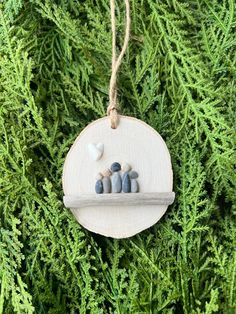 a wooden ornament hanging from a tree filled with green needles and rocks on it's side