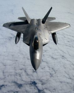 a fighter jet flying through the sky above clouds