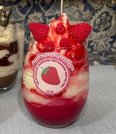 two desserts in glasses with strawberries and whipped cream on the top one is strawberry shortcake