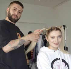 a man cutting the hair of a woman with long blonde hair in front of her