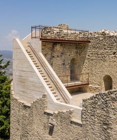 an old stone building with stairs leading up to the second floor and another one in the background