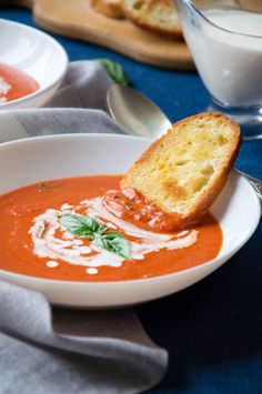 a bowl of tomato soup with bread on the side